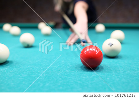 Female player ready to hit red ball on blue pool table Female player ready to hit red ball on blue pool table 101761212