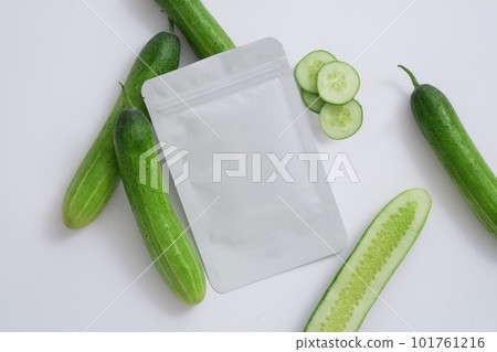Facial beauty sheet mask without label arranged with some Cucumbers against white background. Branding mockup for skin care product extracted from Cucumber (Cucumis sativus) 101761216