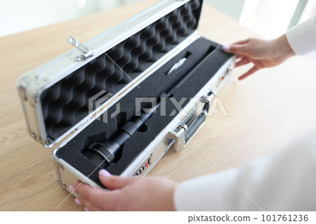 Woman opens silver case with modern Laowa lens for camera 101761236
