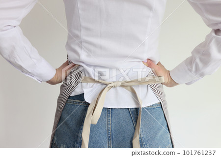 Slim housewife puts on apron and stands with hands on hips 101761237