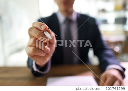 Successful manager points pen to camera sitting at table 101761299