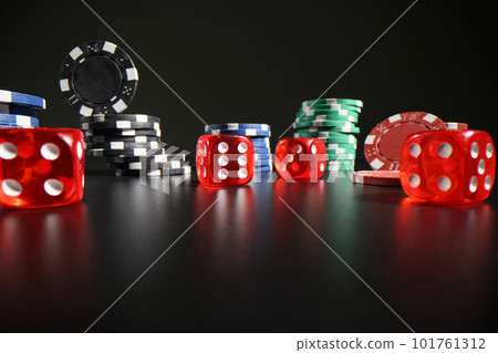Red dice with white dots scattered on table near poker chips 101761312