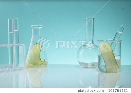 Laboratory glassware containing Cucumber slices are decorated on blue background. Blank space to display natural beauty product of Cucumber (Cucumis sativus) extract Laboratory glassware containing Cucumber slices are decorated on blue background. Blank space to display natural beauty product of Cucumber (Cucumis sativus) extract 101761381
