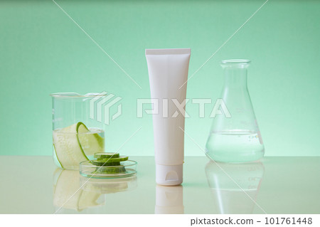 Front view of white bottle without label decorated with laboratory glassware on pastel background and cucumber slices. Research concept of cucumber extracts for cosmetics Front view of white bottle without label decorated with laboratory glassware on pastel background and cucumber slices. Research concept of cucumber extracts for cosmetics 101761448