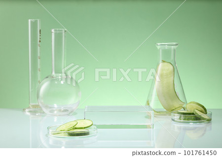 Front view of lab glassware decorated on pastel background with cucumber slices. Empty transparent podium for display cosmetic of cucumber extract. Concept of scientific research in the laboratory 101761450