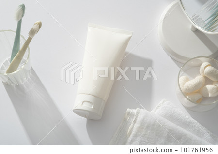 A glass containing toothbrushes decorated with a tube, table mirror, towel and several silkworm cocoons. Natural cosmetic concept. Empty label for branding mockup 101761956