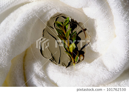 A sample of a mud mask on a terry bath towel with a green sprig. A sample of a mud mask on a terry bath towel with a green sprig. 101762530