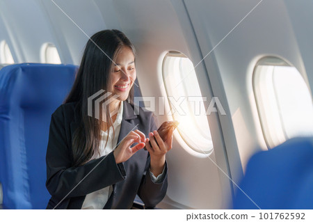 Beautiful Asian business woman chatting with client by mobile phone during flight. working, travel, business concept 101762592