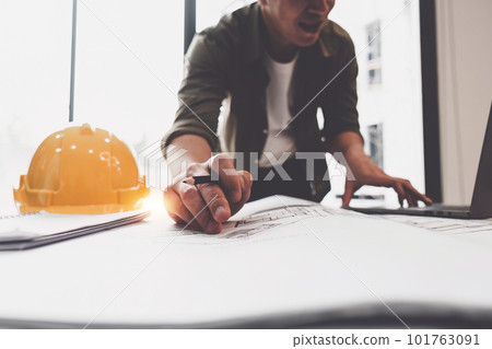 Architect or Engineer working with blueprints for architectural plan, engineer sketching a construction project, green energy concept 101763091