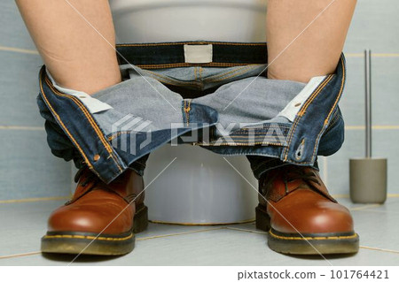 A man sitting on the toilet. A concept from the 1980s. Red punk shoes and jeans. Gender theme and urban culture. Punk subculture and nightlife in the city. 101764421