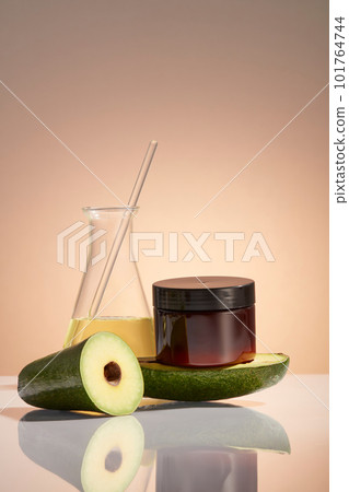 An erlenmeyer flask filled with Avocado essential oil displayed with a jar without label. Beauty product mockup of Avocado (Persea americana) extract. Research natural extract making cosmetic 101764744
