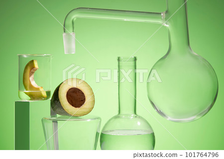 Research scene of cosmetic products with avocado extract in the laboratory with lab glassware and fresh organic avocado slices decorated on green background. 101764796