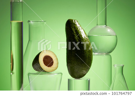 Fresh avocado and essential oil in lab glassware on green background. Research and development natural extract concept. Production of cosmetics based on avocado. 101764797