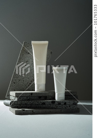 Front view of two white plastic bottle without label are placed on marble stones on dark background. Minimal style for mockup, cosmetic, facial moisturizer cream or facial cleanser. Copy space 101765333