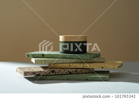 A green jars without label with wooden lid placed on colorful rectangle bricks stacked on brown background. Mockup for cosmetic, moisturizer, mask or scrub. Front view, copy space 101765342