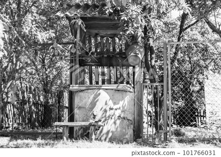 Old well with iron bucket on long forged chain for clean drinking water 101766031