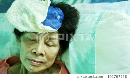 Elderly using cooling gel pad to relieve heat from hot weather 101767258