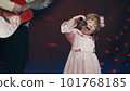 Little girl on stage in vintage dress, she sings into microphone and dances, her father plays acoustic guitar. Color music is shining and smoke is billowing. Father and Child Day, performance on stage 101768185
