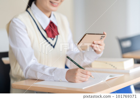 A high school girl using a smartphone to study in a classroom Photography cooperation: Japanese Language School Attached to Chuo College of Technology 101769371