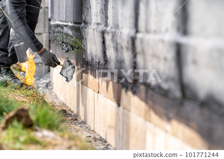 installation of asphalt insulation on the wall of the building with trowel installation of asphalt insulation on the wall of the building with trowel 101771244