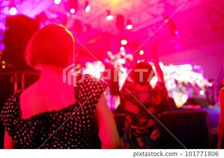 Woman dancing during concert against neon light Woman dancing during concert against neon light 101771806