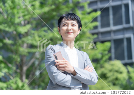 Portrait of a career woman holding a smartphone in the fresh green outdoors Portrait of a career woman holding a smartphone in the fresh green outdoors 101772032