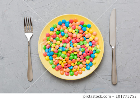 cutlery on table and sweet plate of candy. Health and obesity concept, top view on colored background 101773752