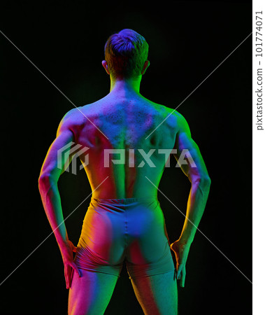 Contemporary art ballet. Young flexible athletic man, dancer posing over dark studio background with neon light. Modern style dancer. Body in glow 101774071