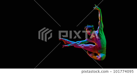 Banner with one young man, ballet dancer jumping in air over dark studio background with neon light. Copy space for ad, text. Freedom 101774095