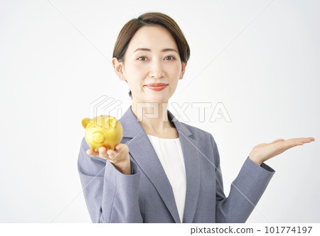 Business woman holding a piggy bank and pointing to the right with her palm White background Business woman holding a piggy bank and pointing to the right with her palm White background 101774197
