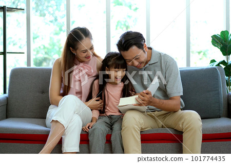 Happy Asian family, father, mother, and daughter living together in the living room. Parent spending a time with their lovely daughter in the free time in weekend together. Happy Asian family, father, mother, and daughter living together in the living room. Parent spending a time with their lovely daughter in the free time in weekend together. 101774435