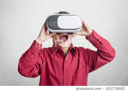 Excited male kid wears virtual relaity goggles, being glad to see fantastic pictures, lives in other world of illusions, isolated over white background. Technology, augmented reality and entertainment Excited male kid wears virtual relaity goggles, being glad to see fantastic pictures, lives in other world of illusions, isolated over white background. Technology, augmented reality and entertainment 101776082