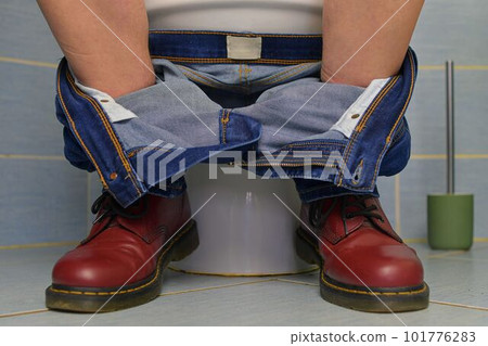 A man sitting on the toilet. A concept from the 1980s. Red punk shoes and jeans. Gender theme and urban culture. A man sitting on the toilet. A concept from the 1980s. Red punk shoes and jeans. Gender theme and urban culture. 101776283