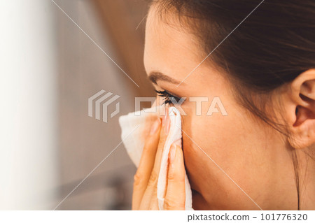 Close up side view woman cleaning her eye make up with a cotton pad Close up side view woman cleaning her eye make up with a cotton pad 101776320