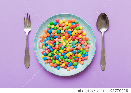 cutlery on table and sweet plate of candy. Health and obesity concept, top view on colored background 101776908