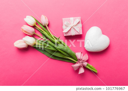 Pink tulips flowers and gift or present box on colored table background. Mothers Day, Birthday, Womens Day, celebration concept. Space for text top view Pink tulips flowers and gift or present box on colored table background. Mothers Day, Birthday, Womens Day, celebration concept. Space for text top view 101776967