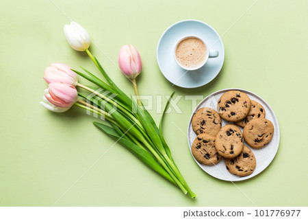 Cup of coffee mug with coffee, cookies and tulips on a colored background. Greeting spring card top view 101776977