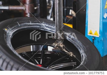 Wheel with tire on tire changing machine in auto repair service. 101779751