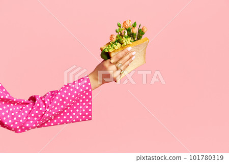Portrait with female hand holding sandwich with flowers inside on pink studio background. Close up. Healthy life style Portrait with female hand holding sandwich with flowers inside on pink studio background. Close up. Healthy life style 101780319