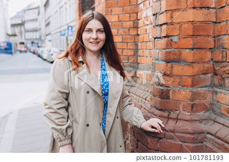 Beautiful redhead girl posing outdoors. Outdoor fashion portrait of elegant, luxury woman wearing beige coat. Urban lifestyle concept. 101781193