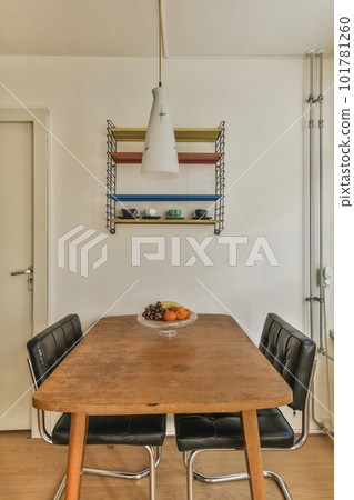 a dining table and chairs in a room with white walls, wood flooring and shelves on the wall above it 101781260