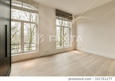 an empty room with wood flooring and large windows looking out onto the trees in the photo is taken from inside 101781277