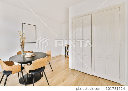 a dining room with white walls and wood flooring the table is surrounded by four chairs in front of the door 101781324