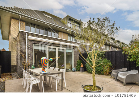 a patio with chairs and a tree in the middle of the yard, next to an outdoor dining set up 101781409