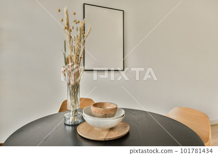flowers in a glass vase on a black table with a white plate and wooden bowl sitting on the table next to it flowers in a glass vase on a black table with a white plate and wooden bowl sitting on the table next to it 101781434