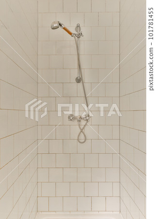 a shower with white tiles on the wall behind it and an orange brush in the corner of the shower head a shower with white tiles on the wall behind it and an orange brush in the corner of the shower head 101781455
