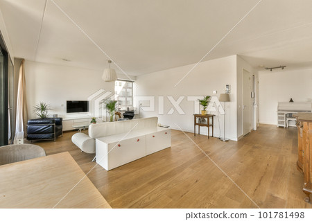 a living room with wood flooring and white couches in the center of the room is an open kitchen 101781498