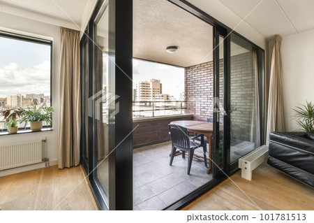 a living room with sliding glass doors that open up to the balcony and view of cityscaing buildings in the distance a living room with sliding glass doors that open up to the balcony and view of cityscaing buildings in the distance 101781513