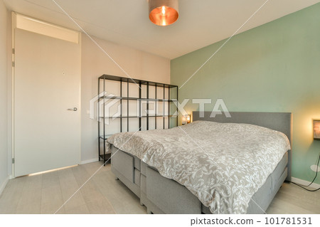 a bedroom with a bed and two lamps on either side of the bed, in front of a green wall a bedroom with a bed and two lamps on either side of the bed, in front of a green wall 101781531