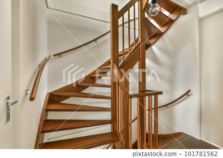 a wooden spiral staircase in a white room with hardwood flooring and wood handrails on the wall behind a wooden spiral staircase in a white room with hardwood flooring and wood handrails on the wall behind 101781562
